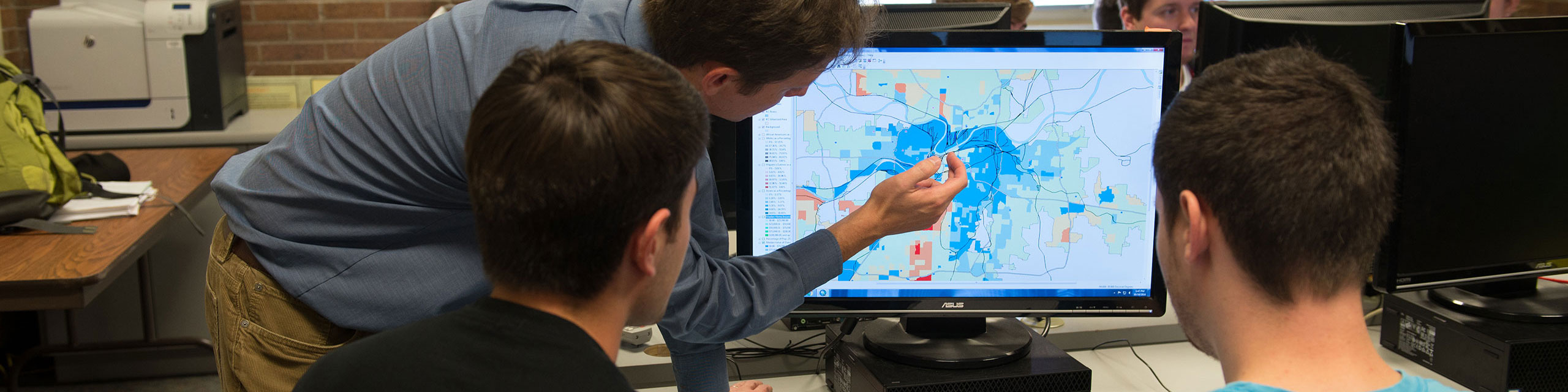 Professor helping student analyse a map on a screen.